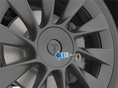 一个从轮毂螺母工具指向轮毂螺母罩上 Tesla“T”底部下方圆形凹痕的箭头