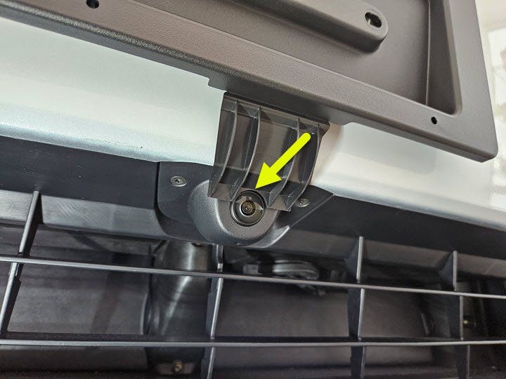 前车牌架的照片，箭头指向与前格栅上方摄像头对齐的导片